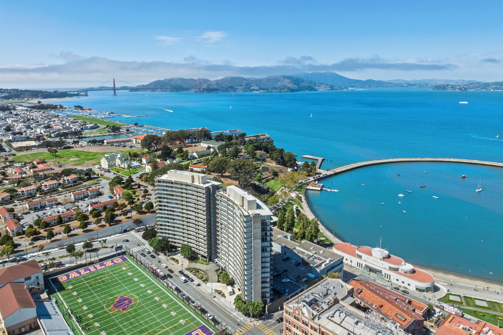 Wide aerial photograph of 1000 North Point Street in San Francisco, showing a high-rise residential building near Fisherman's Wharf with the San Francisco Bay, Alcatraz, and the Golden Gate in the background.