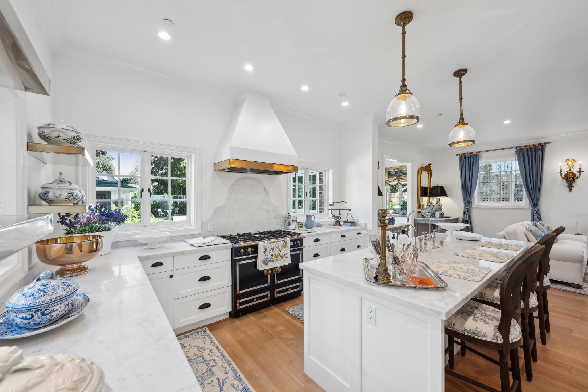 All-white French country kitchen with black La Cornue range, black cup-pull hardware, marble countertops, and farmhouse sink at 853 D Street, Petaluma