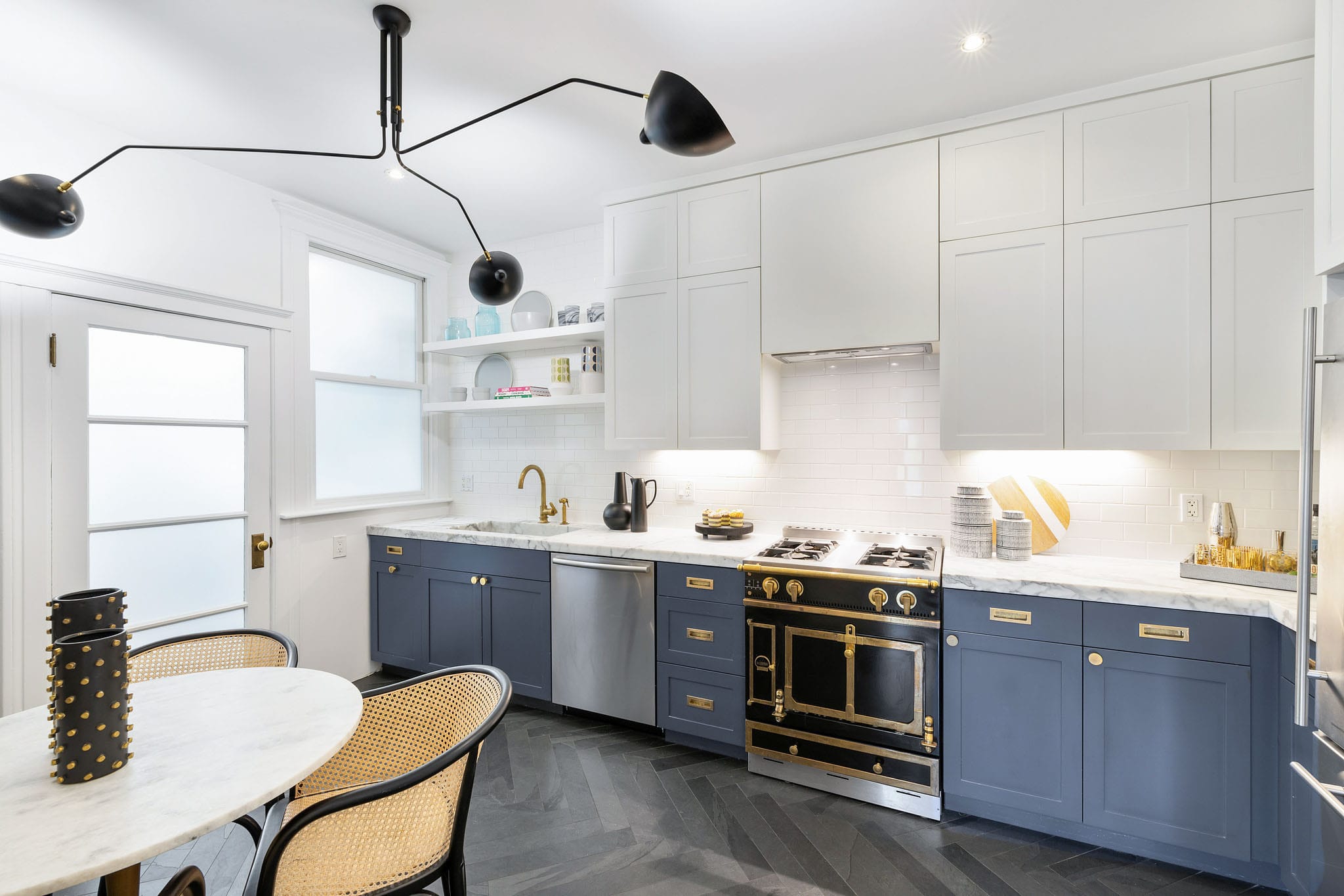 Dusty blue lower cabinets with brass hardware and black La Cornue range in San Francisco kitchen.