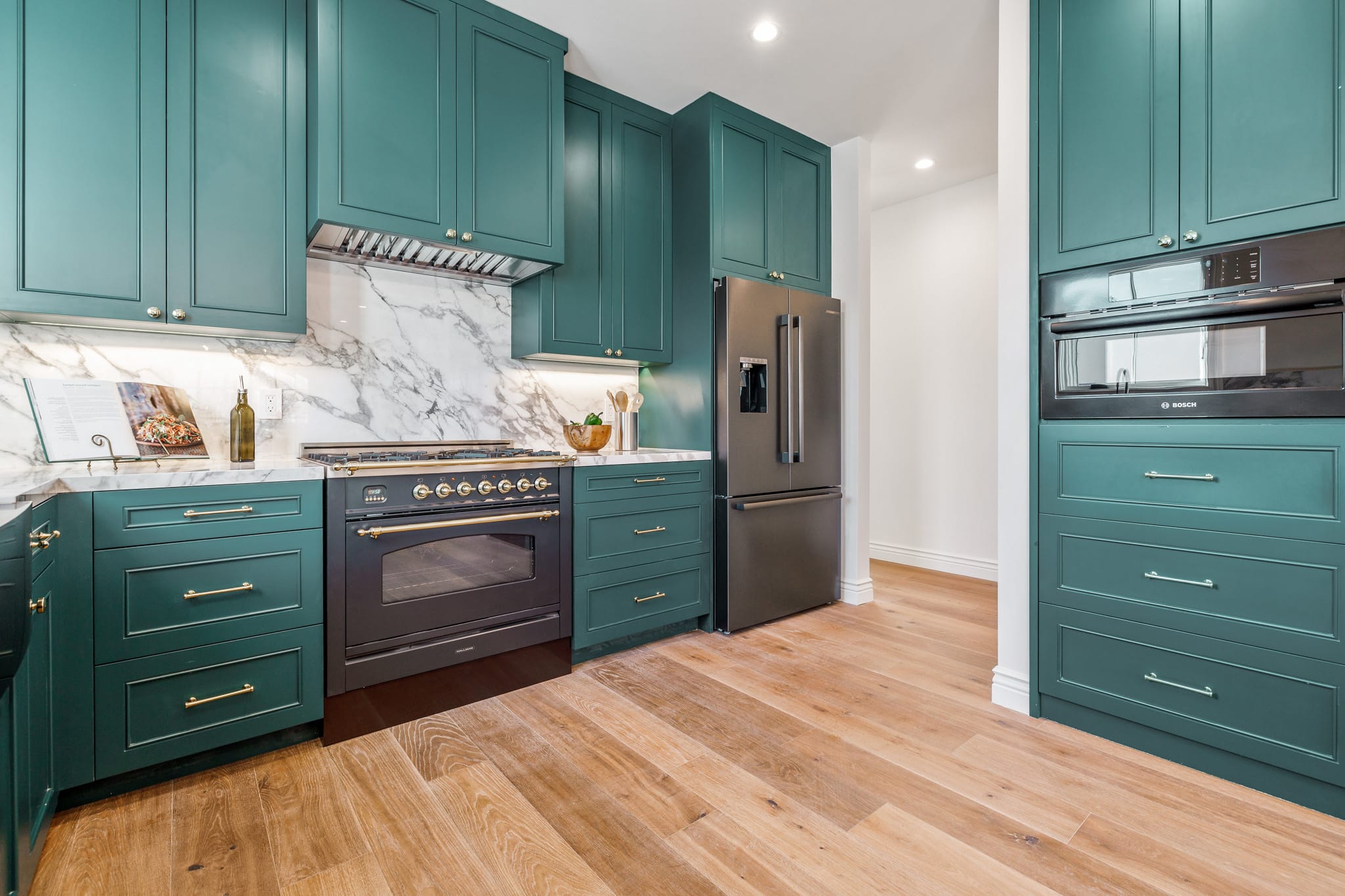 Full kitchen run with teal sapphire cabinets, black range, stainless refrigerator, marble backsplash, and hardwood floors at 115 Humboldt Road