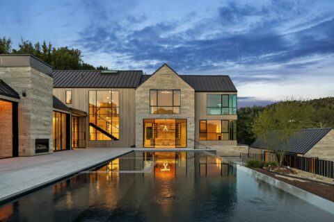Shot of a home's facade at Twilight with a pool in the foreground and a modern, two-story home in the back