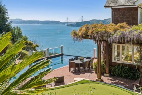 Shot of a backyard with a putting green, an outdoor table and chairs, and the Golden Gate Bridge in the distance