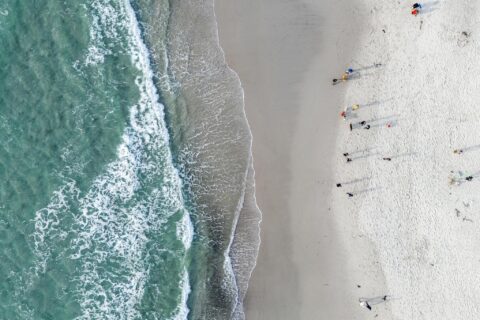 An aerial shot looks down at where the surf meets the sand