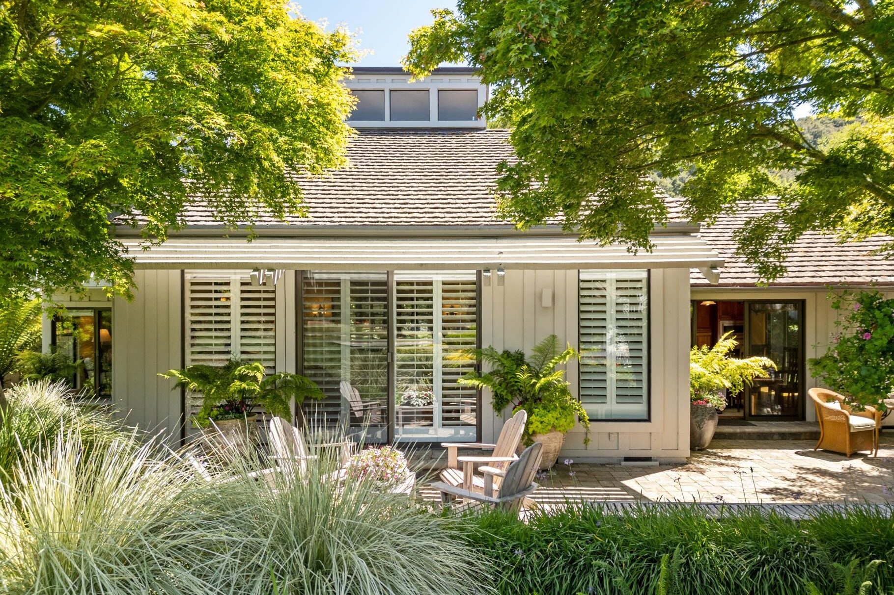 Exterior of a Carmel Valley Ranch home with Adirondack chairs and lush garden.