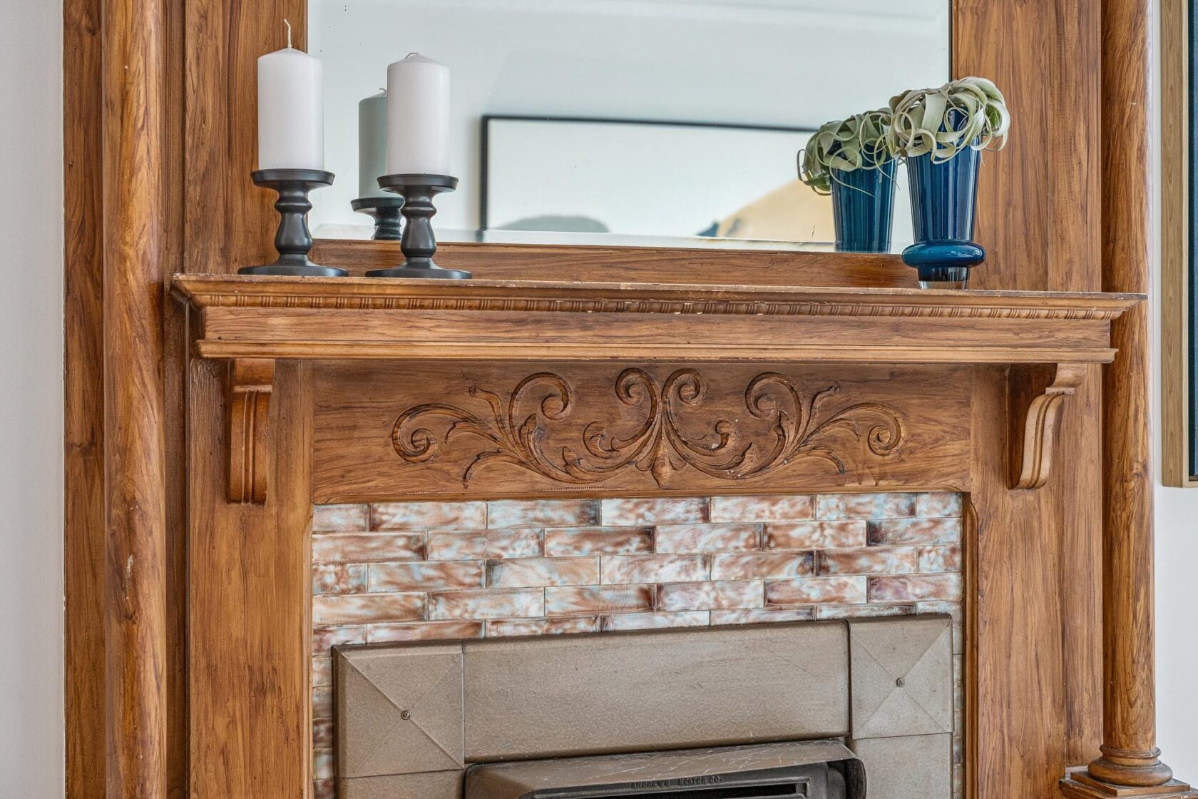 A richly detailed original Victorian fireplace mantel in warm redwood, featuring hand-carved acanthus scroll relief work, with tile surround below.