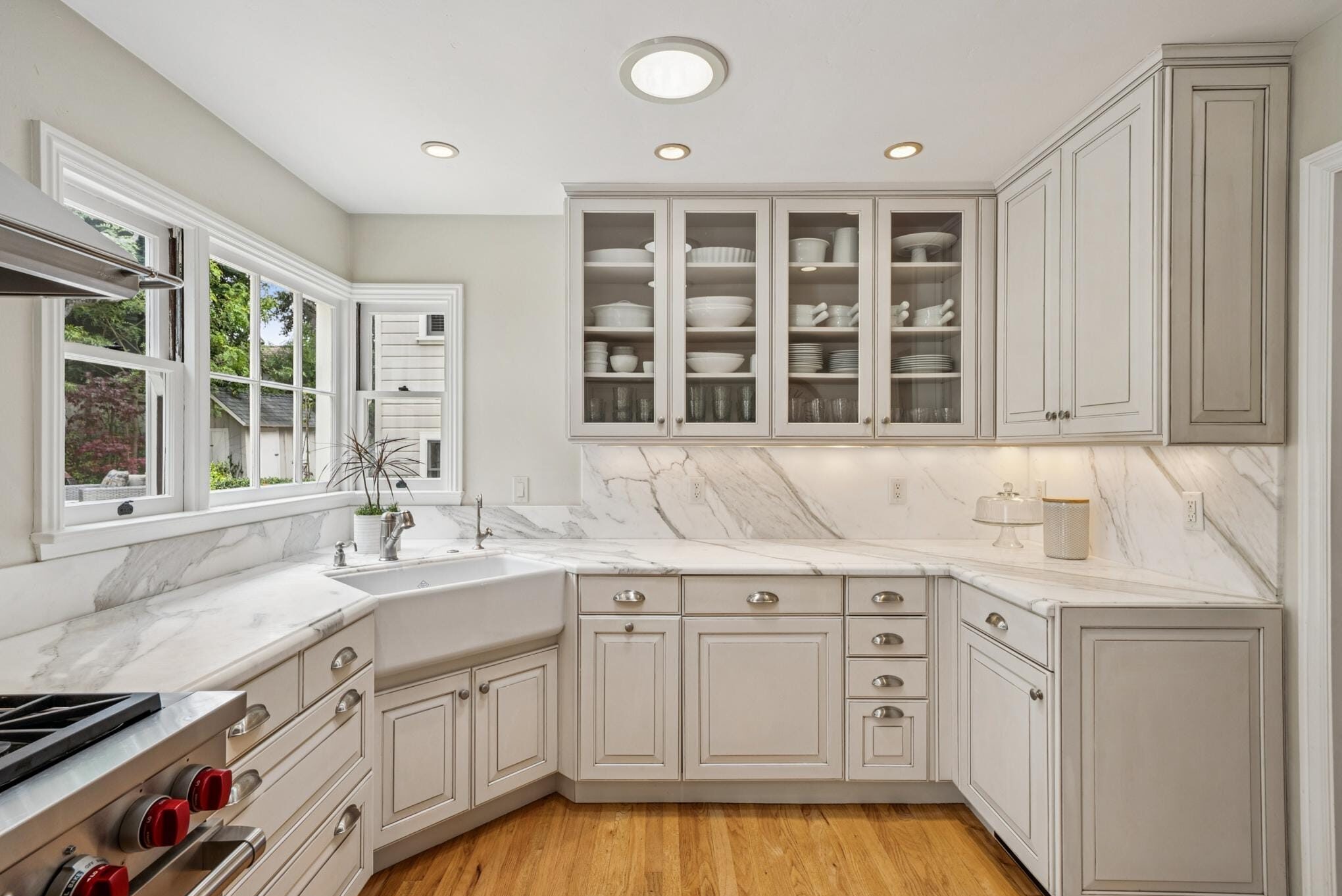 Gourmet kitchen with grey cabinetry, Calcutta marble countertops, farmhouse sink, and glass-front cabinets in a Carmel, CA home.