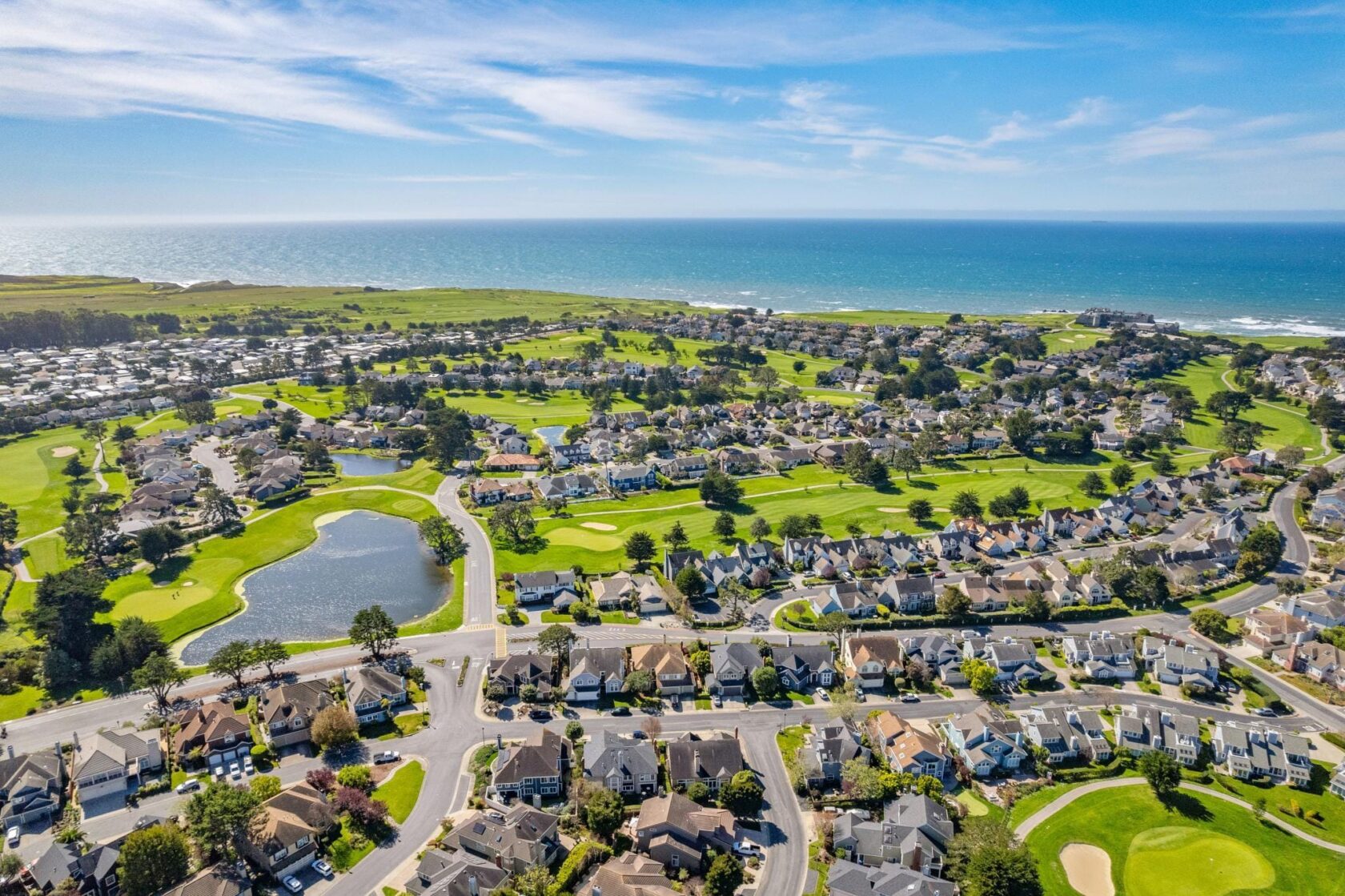 Drone view overlooking a golf course neighborhood and the Pacific Ocean in Half Moon Bay.