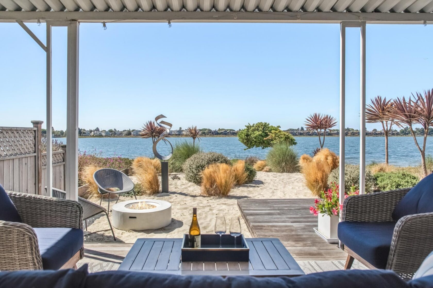 Covered waterfront patio with fire pit lit, seating staged, and clutter removed for a listing shoot