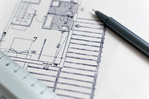 Hand-drawn architectural floor plan with measurements, a drafting pencil, and a ruler