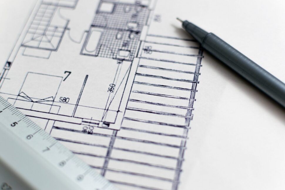 Hand-drawn architectural floor plan with measurements, a drafting pencil, and a ruler