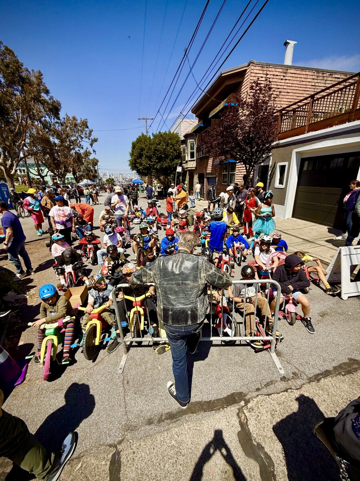 A crowd of kids on Big Wheels trikes wait at the starting line