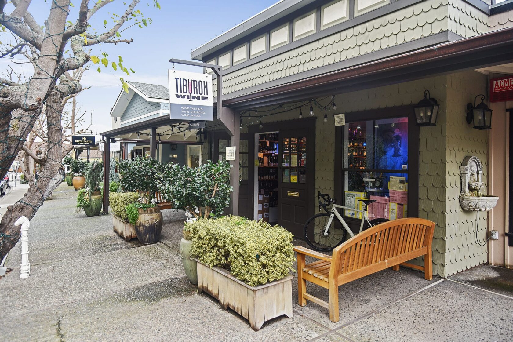 Exterior of Tiburon Wine shop on Main Street in Tiburon CA with potted plants, wooden bench, and bicycle out front